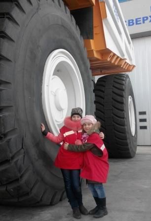 Фотография детей сирот на фоне большого колеса от "БелАЗ".